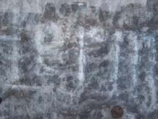 Hinter einer Glasplatte ist der Name Hermann Krone eingeritzt.
