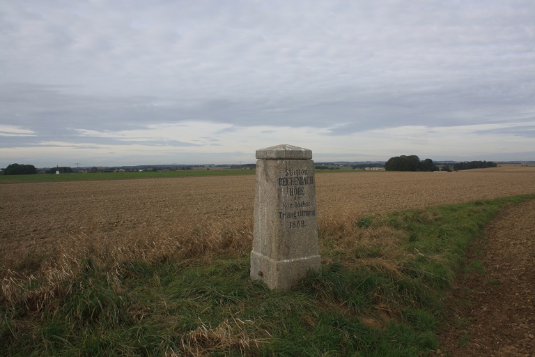 Die Vermessungsaäule steht auf einem Feld.